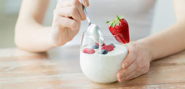 Frau isst Joghurt als Probiotika.