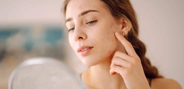 Frau prüft Haut im Spiegel.