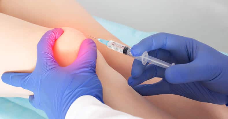 Frau bekommt Hyaluronspritze ins Knie injiziert.